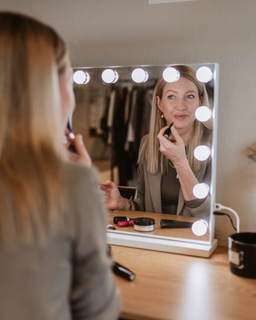 Kathi Walter schminkt sich vor einem beleuchteten Spiegel.