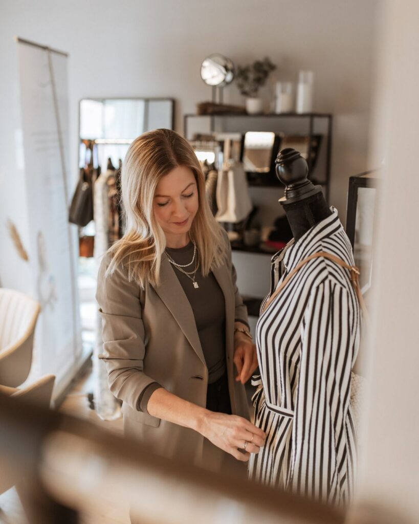 Kathi Walter prüft Kleidung auf einer Kleiderstange.