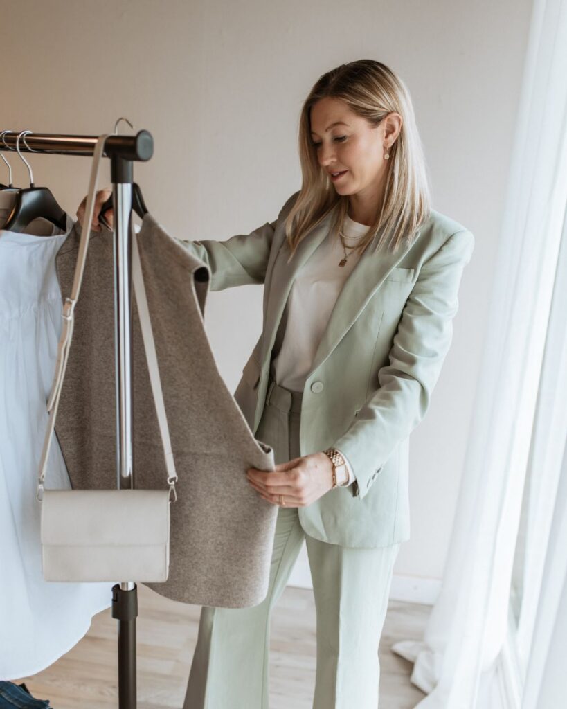 Kathi Walter hält zwei Kleidungsstücke hoch, um Outfits zu vergleichen.